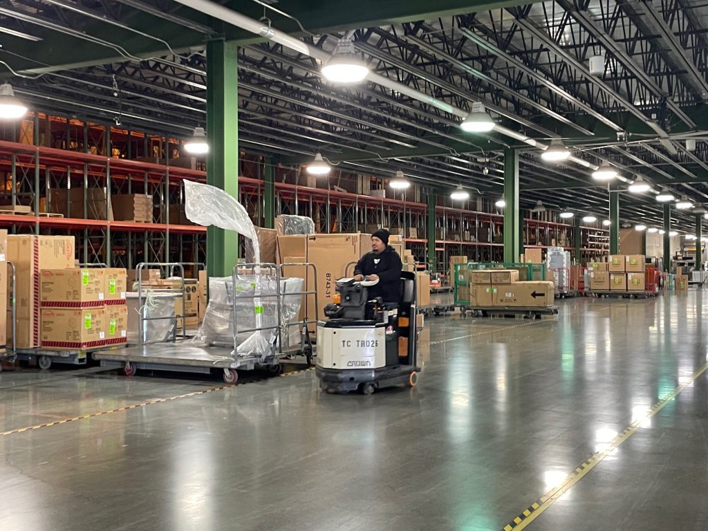Furniture Warehouse racking with product. Man driving a forklift.