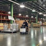 Furniture Warehouse racking with product. Man driving a forklift.