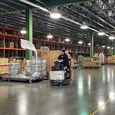 Furniture Warehouse racking with product. Man driving a forklift.