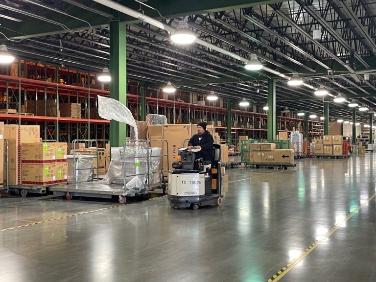 Furniture Warehouse racking with product. Man driving a forklift.
