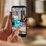 Decorating Apartment: Woman Holding Smartphone, using Augmented Reality Interior Design Software Chooses 3D Furniture for Home. Pick a Stylish Chair for the Living Room. Over Shoulder Close-up Screen