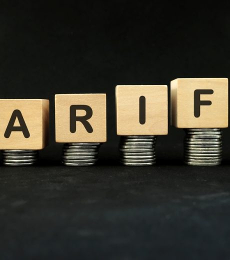 Increase tariff tax concept. Word in wooden blocks with increasing stack of coins.