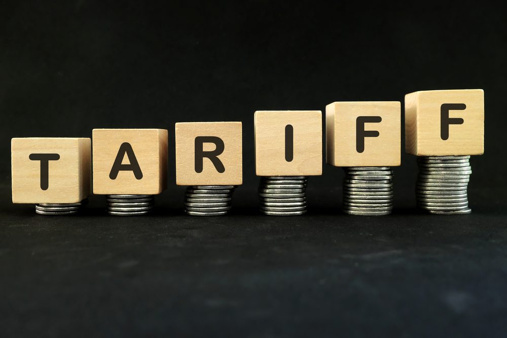 Increase tariff tax concept. Word in wooden blocks with increasing stack of coins.