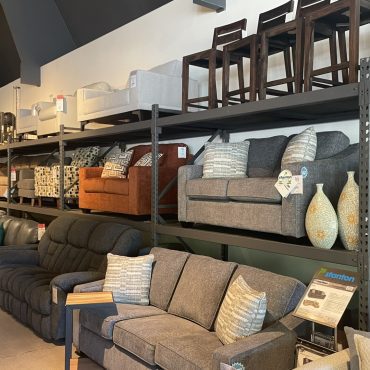Stacked furniture inventory in a furniture store. Featuring chairs and sofas.