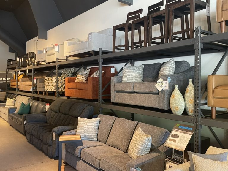 Stacked furniture inventory in a furniture store. Featuring chairs and sofas.