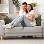 Happy couple sitting on sofa hugging.