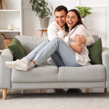 Happy couple sitting on sofa hugging.