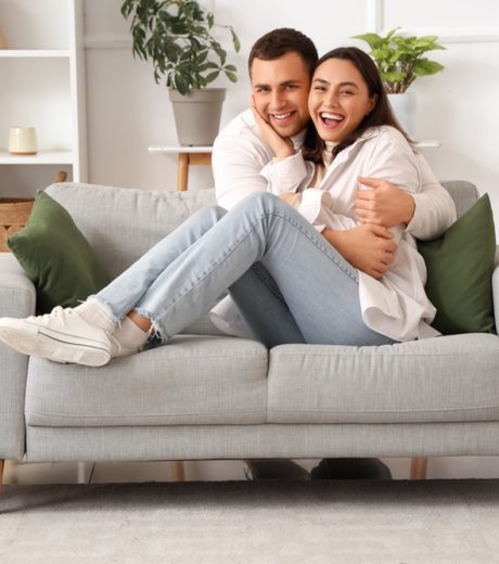 Happy couple sitting on sofa hugging.