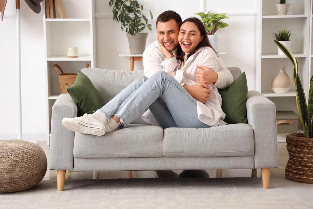 Happy couple sitting on sofa hugging.