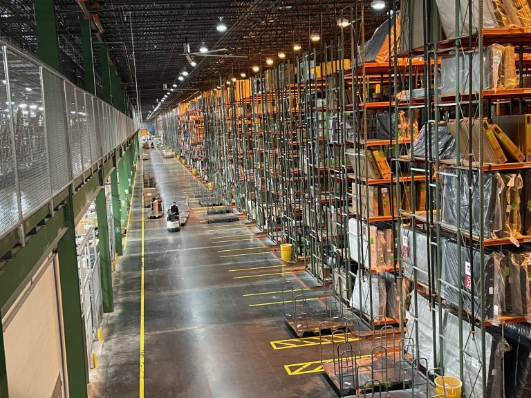 Furniture warehouse with racking and rows of furniture.